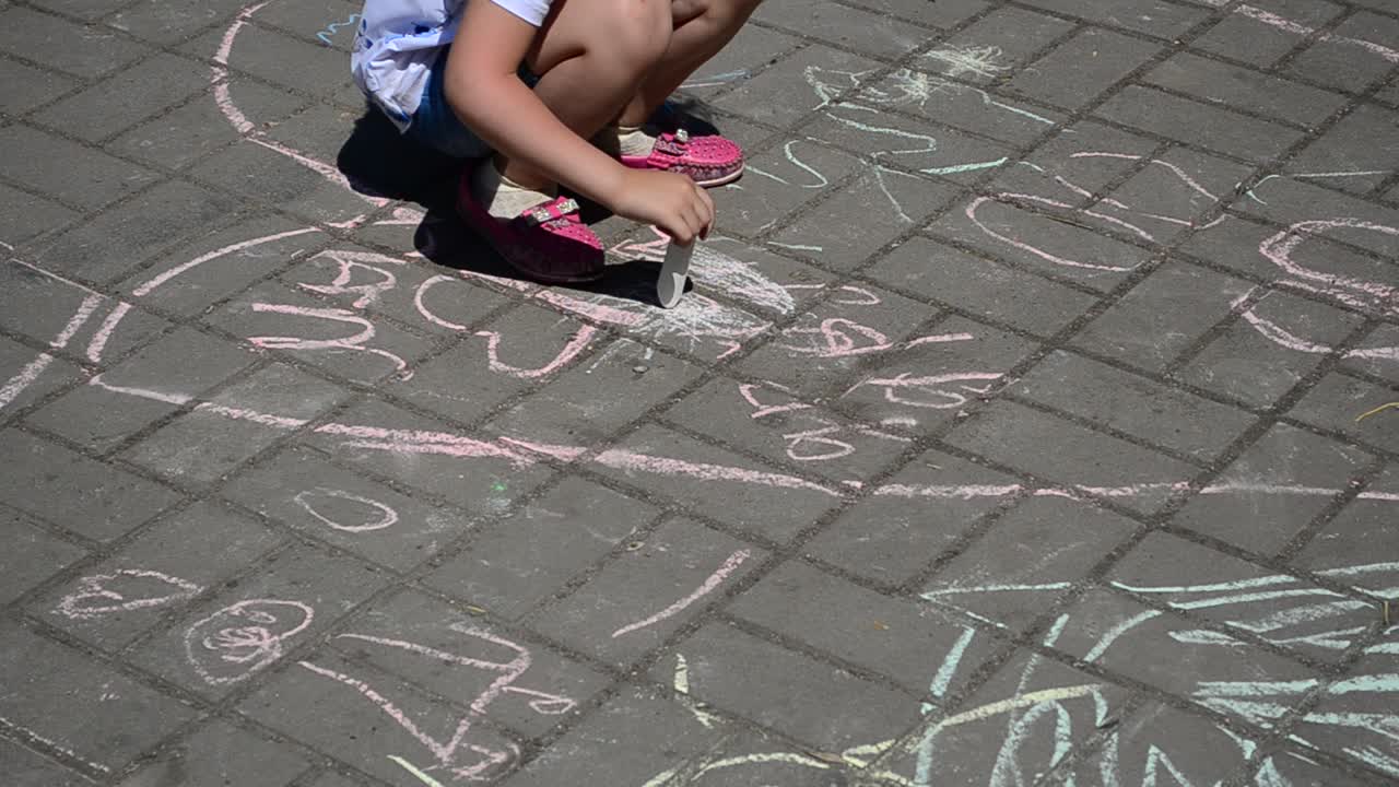 Child draws with chalk. Actions in honor of day of a family. Shooting in the summer