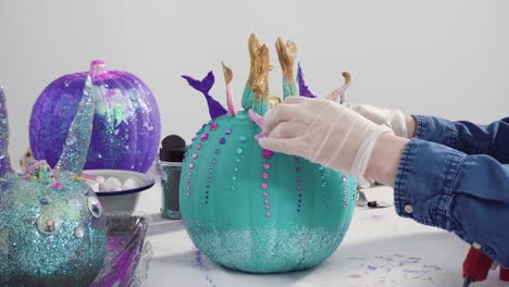 mother and daughter decorating art pumpkins with glitter
