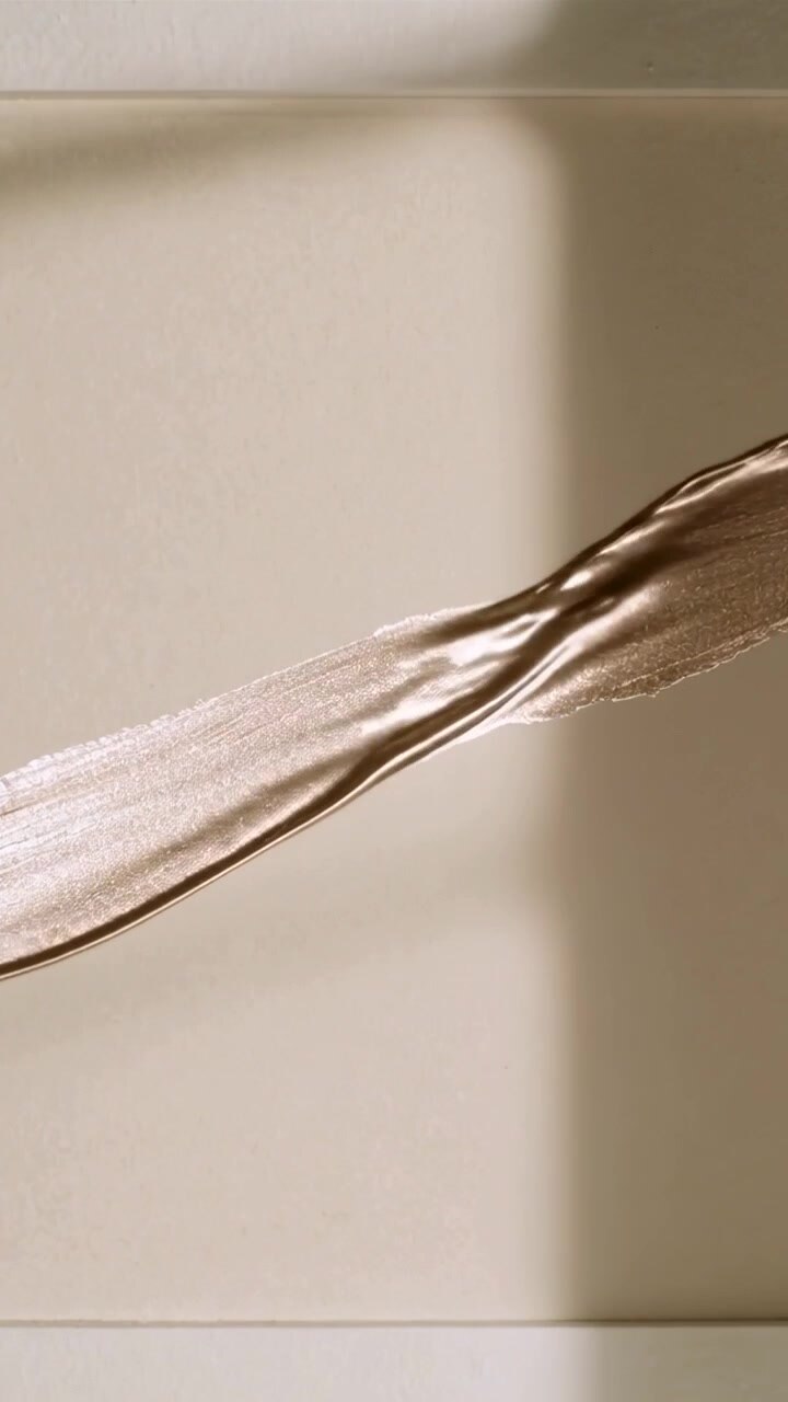 Video verticale: Strumento che trascina una striscia perlescente su un pannello beige in studio, mostrando la lucentezza