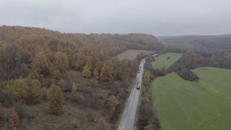 Follow-through-drone-shot-of-cars-moving-on-a-road-above-the-Balkan-Mountains,-located-in-the-municipality-of-Dimovo-in-Bulgaria