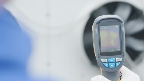 technician uses a thermal imaging infrared thermometer to check the condensing unit heat exchanger