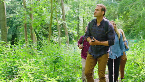 group of friends posing for selfie in countryside taking picture on phone as they hike along path