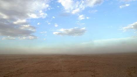 Sand-blowing-on-an-empty-waterless-pan-during-a-small-sandstorm-in-Namibia,-Africa