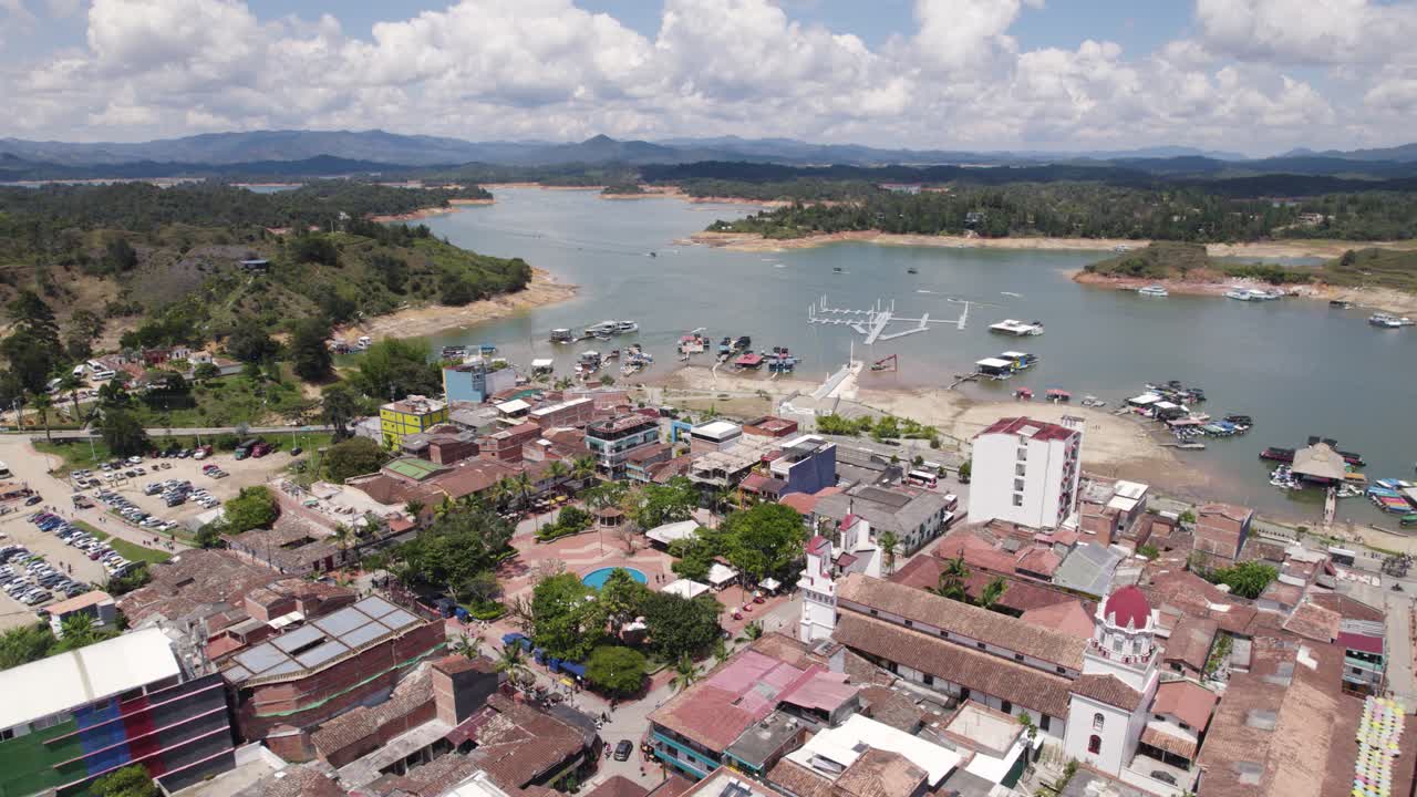 guatapé, colombia, mostrando la vibrante ciudad y el sereno lago con barcos, vista aérea