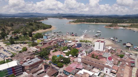 Guatapé,-Colombia,-Mostrando-La-Vibrante-Ciudad-Y-El-Sereno-Lago-Con-Botes,-Vista-Aérea