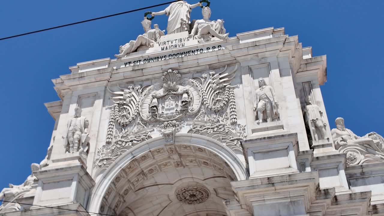 Maestoso Arco di Rua Augusta che si erge imponente in Piazza del Commercio, Lisbona, Portogallo, sotto un vibrante cielo blu. Ripresa con inclinazione verso l'alto