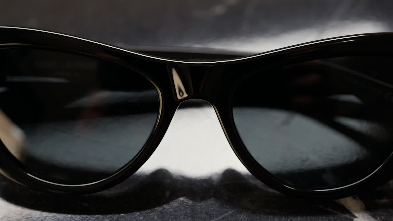 Close up of a black pair of sunglasses on a black surface