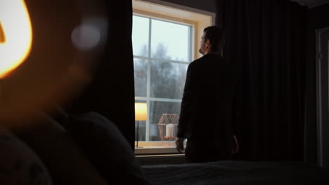 man facing bedroom window showing frustration