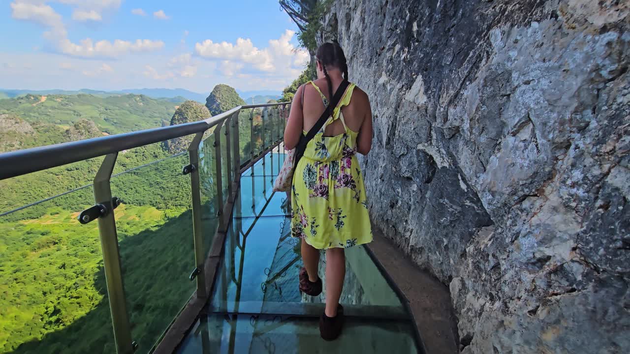 Woman walking on a glass bridge at the Ruyi Peak Ropeway, in Yangshuo, China