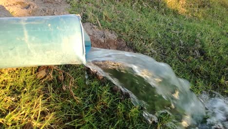 water flowing from a irrigation pipe with green grass in the background