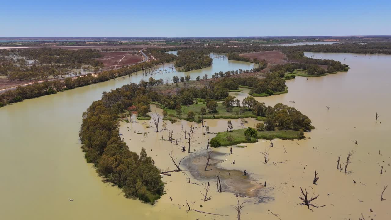 Ripresa aerea di un canale lagunare curvo e delle distese di sabbia circostanti presso la laguna di Wachtels, carrellata media con acqua marrone fango e alberi spezzati