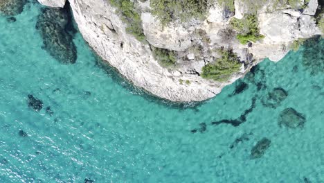 crystal clear turquoise sea and cliff - sunny aerial top down