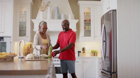 Feliz-Pareja-De-Ancianos-Afroamericanos-Desempacando-Comestibles-En-La-Cocina,-Cámara-Lenta