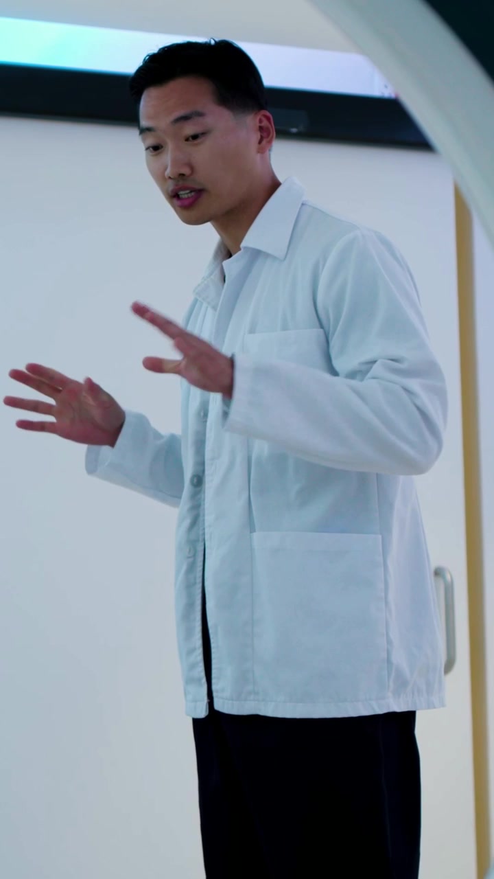 Vertical video: Seeing hand, man in lab coat opening door and entering lab, explaining circular rim