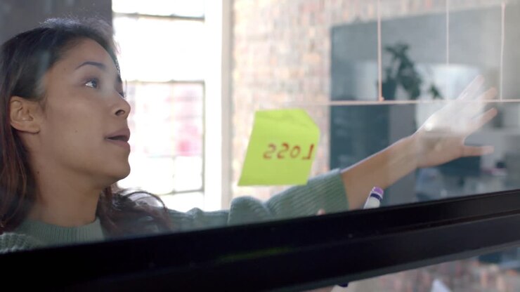 Diverse male and female colleagues in discussion, brainstorming at glass wall in office, slow motion
