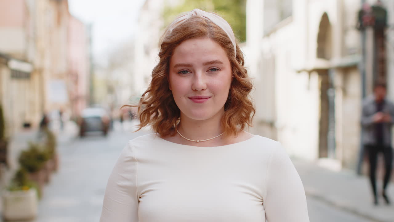 젊은 여성이 스마트폰을 사용하고 문자 메시지를 입력하고 인터넷을 탐색하고 카메라를 보고 일을 마치고 있습니다.