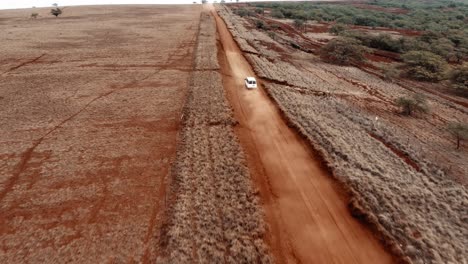 Aerial-over-white-panel-van-police-transport-vehicle-traveling-on-a-generic-rural-dirt-road-on-Molokai-Hawaii-from-Maunaloa-to-Hale-o-Lono