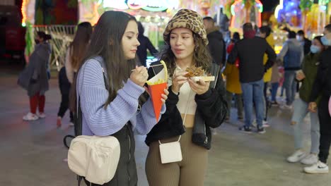 two friends enjoying street food at a night market