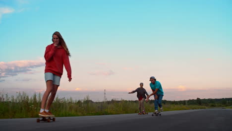 Two-Boys-And-A-Girl-Skateboarding-On-The-Road-In-The-Middle-Of-A-Meadow