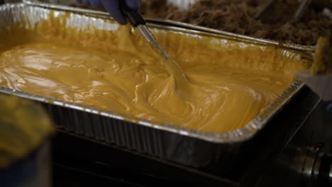 hand mixing nacho cheese sauce, food for sale at the dogwood festival in siloam springs, ar, usa - slow motion, closeup