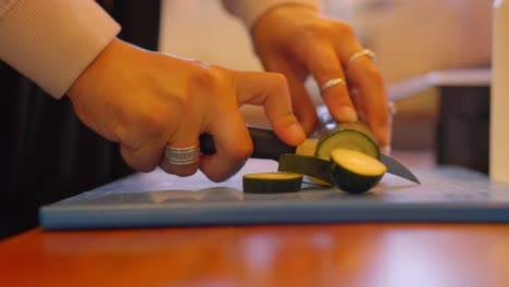 woman cutting cucumber slices in a kitchen