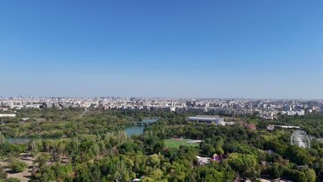 rotating drone view over oraselul copiilor park, surrounded by greenery and lakes with bucharest's skyline in the background, romania