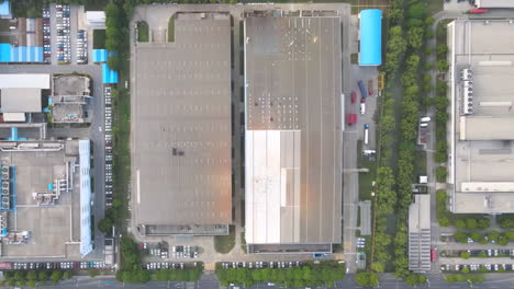 overhead shot of industrial big factory warehouse rooftop. aerial drone shot camera flying forward. factory rooftop, roof windows, ventilation shafts, flat roof of a big manufacture warehouse.