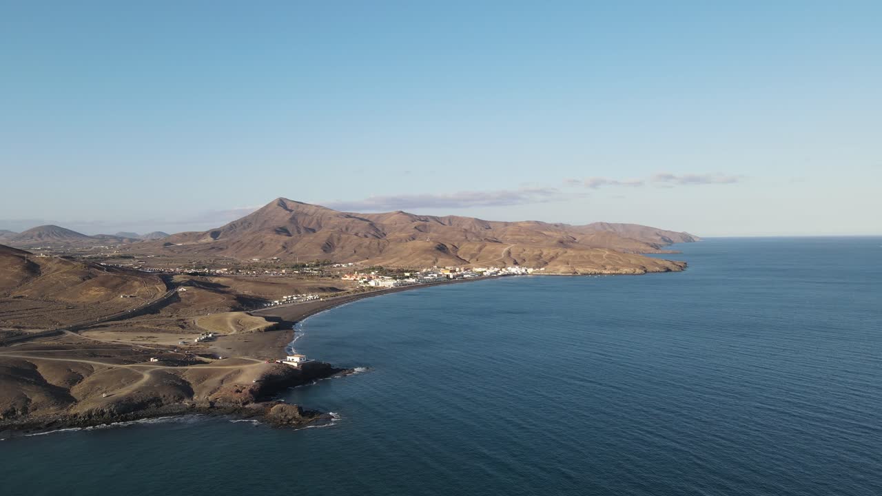 video aéreo de drones de un pequeño pueblo en el lado costero de la isla fuerteventura mientras se pone el sol