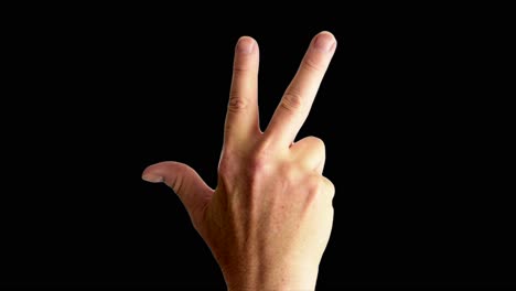 Close-up-shot-of-a-male-hand-throwing-a-classic-gang-sign,-against-a-plain-black-background