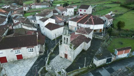 wide angle aerial orbit of old church surrounded by modern buildings in countryside of ourense