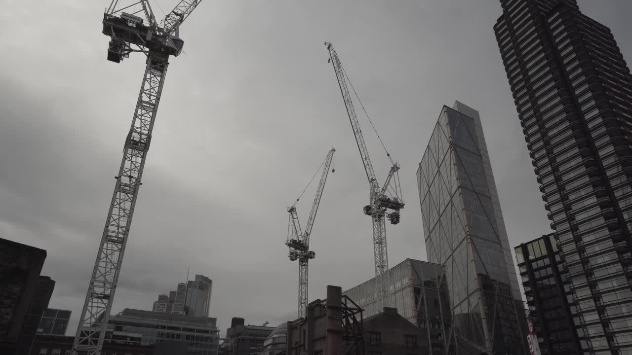 skyscrapers construction view in the city city of london capital england uk. three big cranes resting during cloudy day