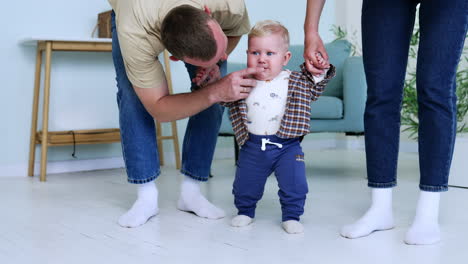 daddy leans to his baby boy to comfort him. parents teaching their baby to walk. first steps concept.