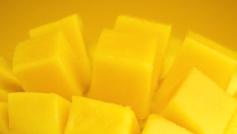 Macro-shot-Slice-mango-cubes-rotating-against-Yellow-background,-Tropical-Fruit