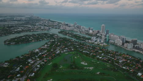 Vista-De-ángulo-Alto-De-Edificios-En-La-Costa-Del-Mar.-Toma-Aérea-De-Barrio-Residencial-Y-Fila-De-Altos-Edificios-De-Apartamentos-Al-Atardecer.-Miami,-Estados-Unidos