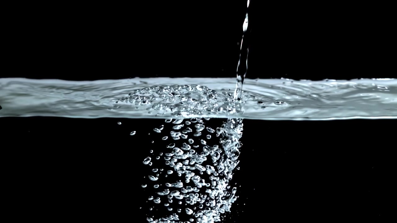Acqua che si versa e ribolle su sfondo nero.
