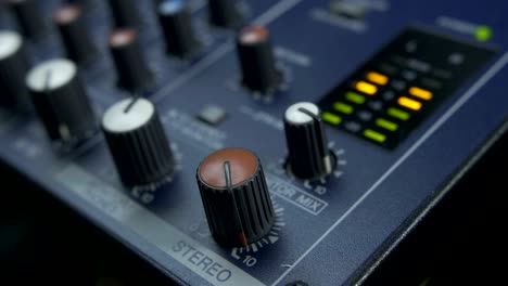 female fingers turning fader knob on audio mixer