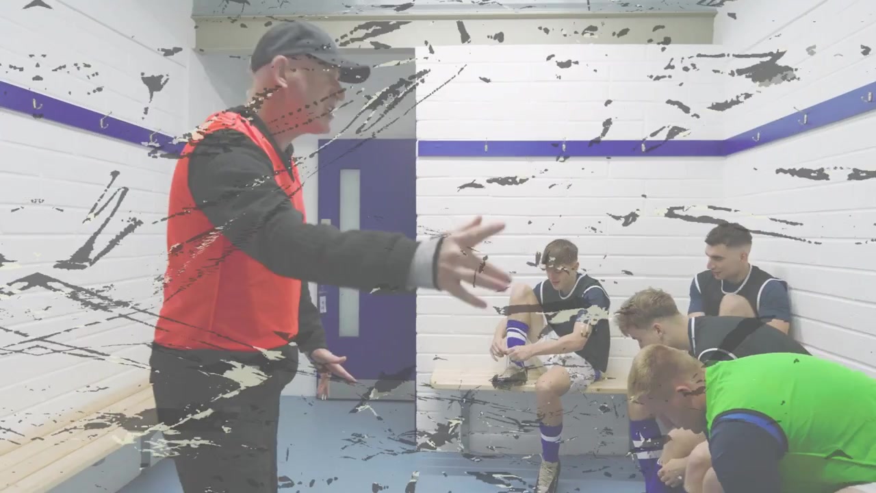 Vertical video: Male coach red bib giving half locker room talk urging team tying boots, copy space