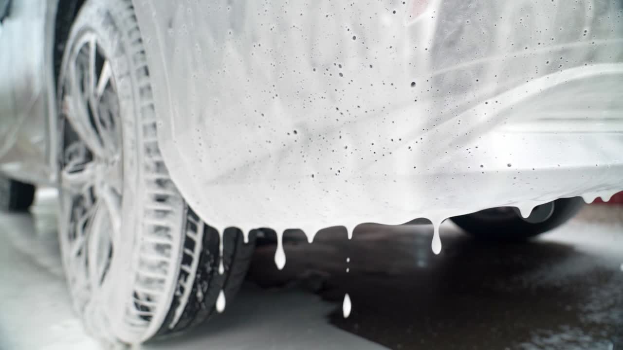 Close-up of car with foam dripping during a wash