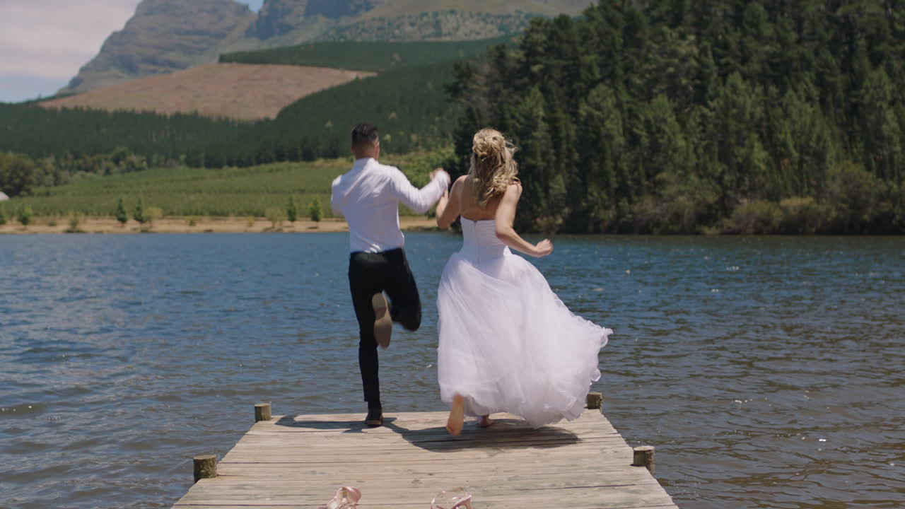 Married couple jumping off jetty in lake bride and groom celebrating ...