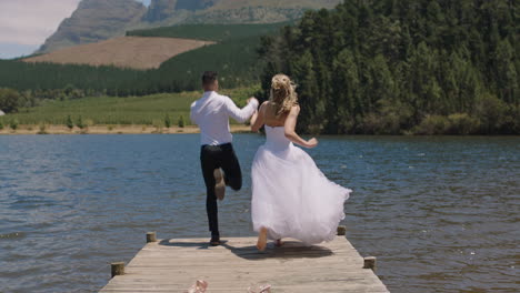 married couple jumping off jetty in lake bride and groom celebrating honeymoon sharing romantic wedding day