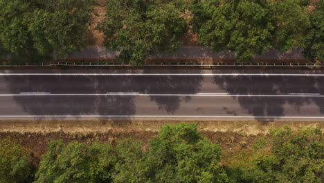 Aerial-shot-of-car-carrying-kayak-on-the-roof-driving-along-the-countryside-road,-drone-point-of-view