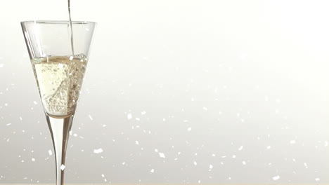 animation of snow falling over champagne glass on white background