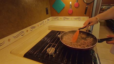 mujer cocinando carne molida con cebolla en una sartén en la cocina de rv
