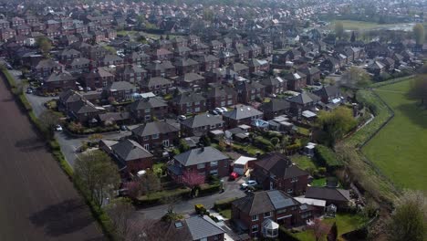 Countryside-housing-estate-aerial-rising-view-flying-over-England-farmland-residential-community-homes