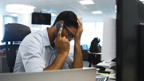 Male-executive-talking-on-telephone-at-desk