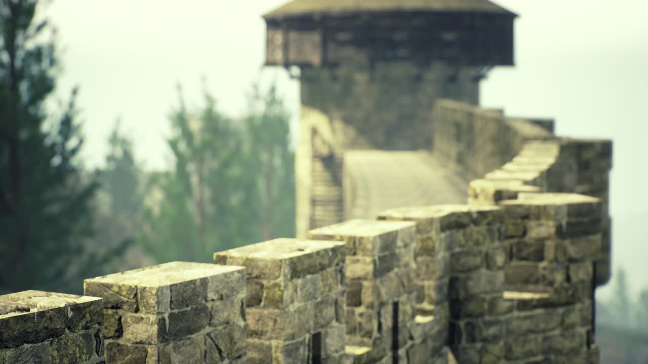 View of ancient stone wall with tower surrounded by trees on a misty day