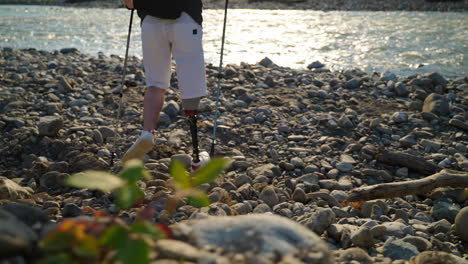 person with prosthetic leg hiking by a river