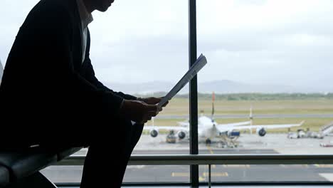 businessman sitting at airport and reading newspaper