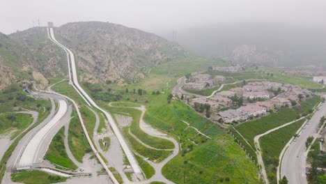 aerial drone time lapse of los angeles aqueduct next to a residential area releasing water to prevent flooding ending drought control and water restrictions