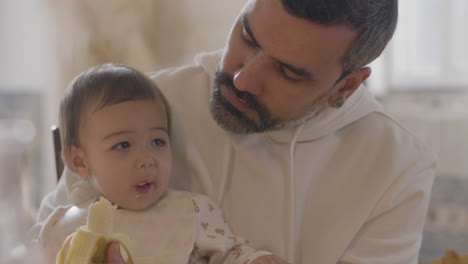 Hübscher-Bärtiger-Vater,-Der-Seine-Kleine-Tochter-Mit-Banane-Füttert